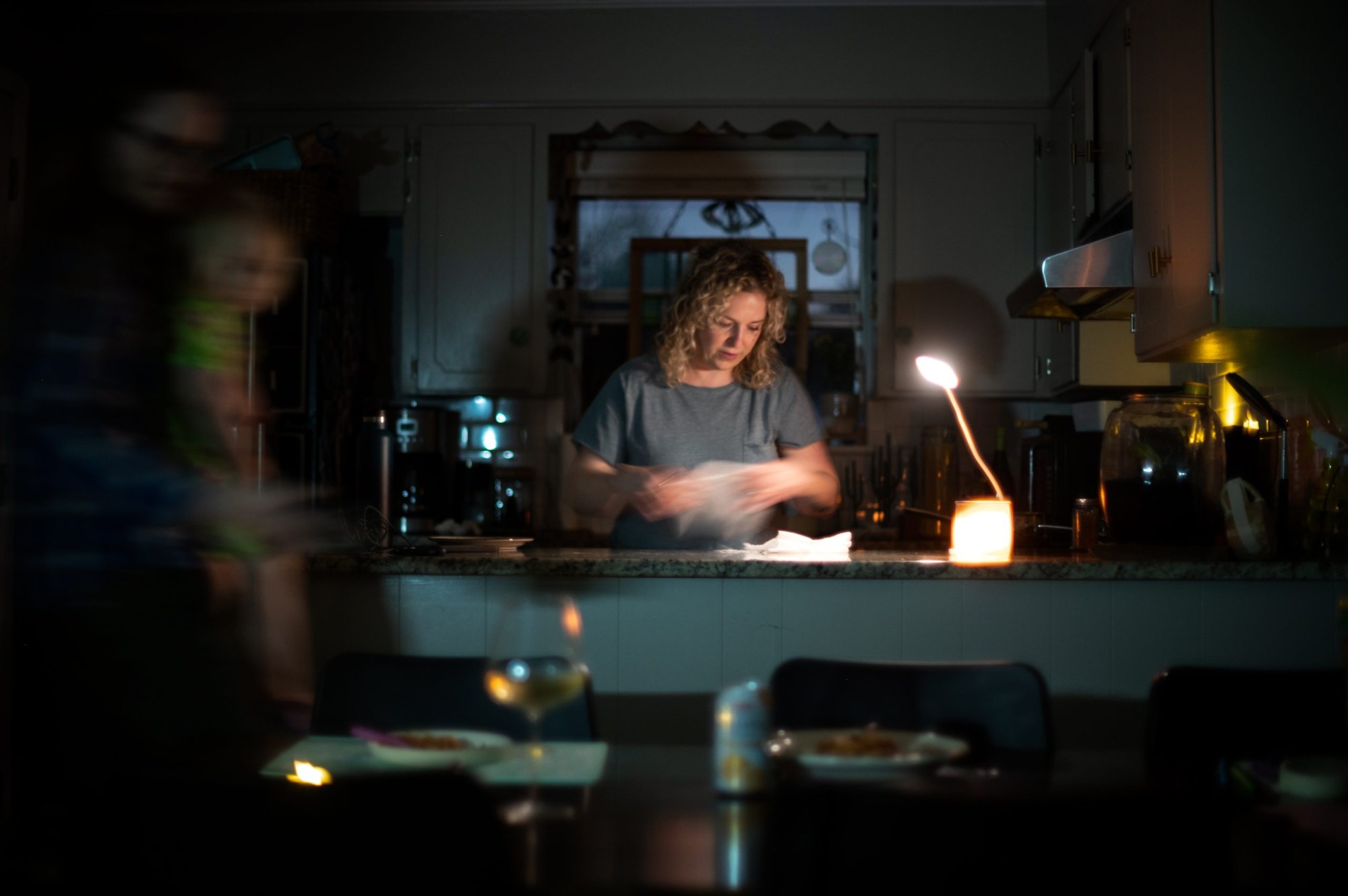 Whitney Morrow serves dinner, cooked on a propane camping stove, by a battery-powered desk light used for working from home in Wooten, Austin on Feb. 6, 2023.
