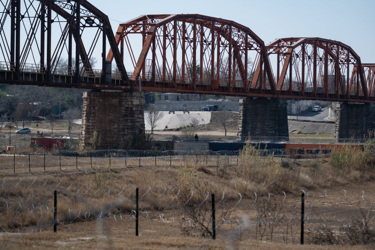 A National Guard soldier sits atop a wall made of shipping containers while watching the U.S.-Mexico border on Feb. 7, 2025 in Eagle Pass.