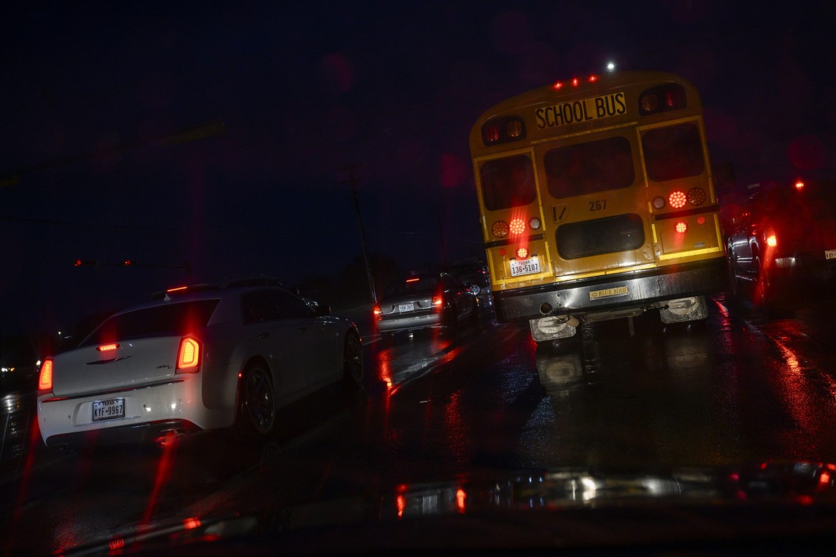A school bus waits at an intersection while driving its morning pickup route before dawn on Sept. 12, 2023 in West Odessa.