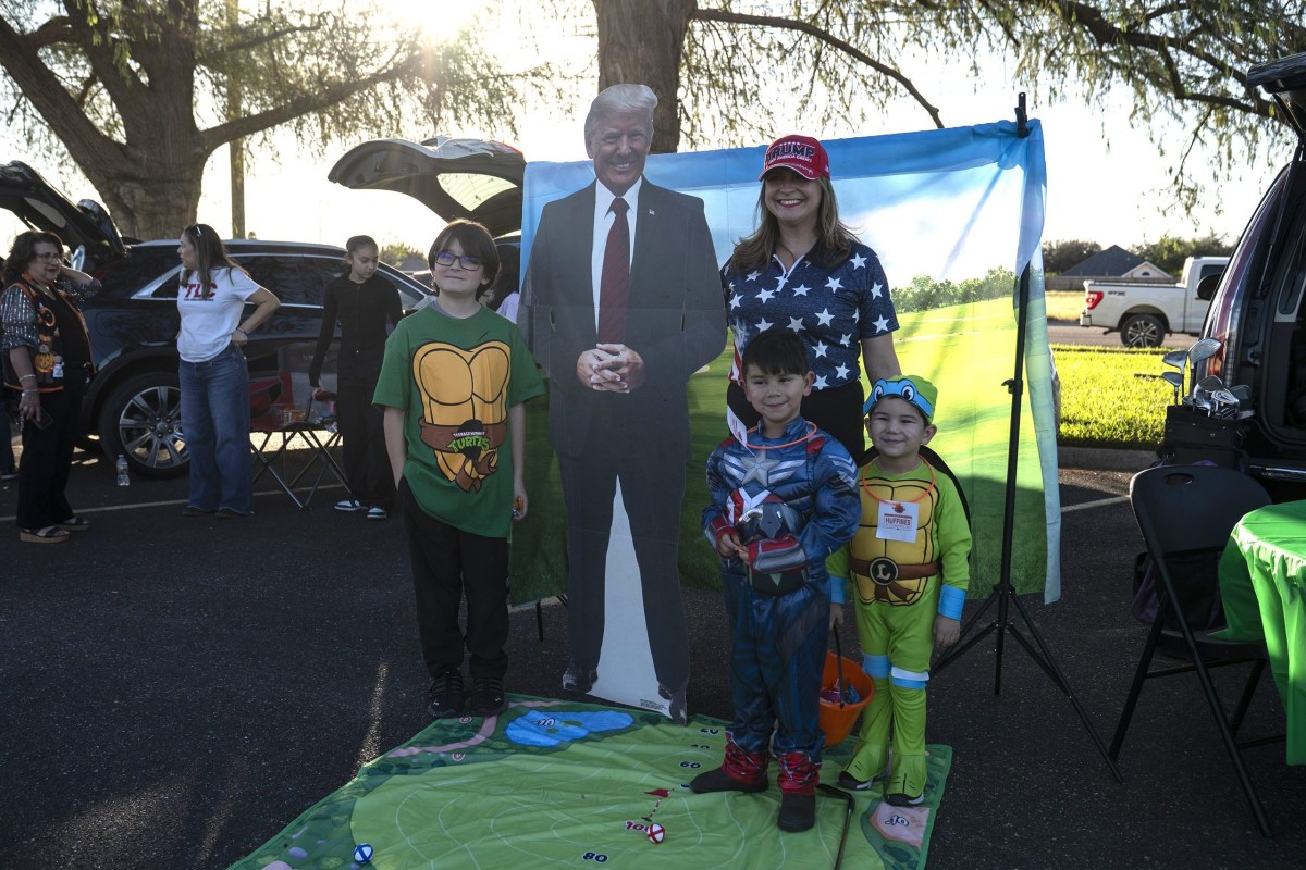 From left: Jagger Johnson, 12, Celeste Cabrera, Jackson Esquivel, 5, and Jett Esquivel, 3, pose for a photo with a cardboard cutout of President Donald Trump during a trunk-or-treat community event at the Hidalgo County Republican Party Headquarters in McAllen on Oct. 30, 2025.