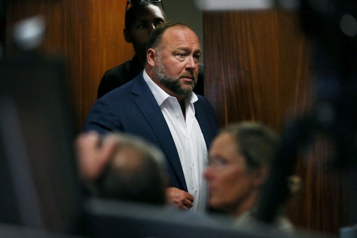 Alex Jones walks into the courtroom in front of Scarlett Lewis and Neil Heslin, the parents of 6-year-old Sandy Hook shooting victim Jesse Lewis, at the Travis County Courthouse in Austin on July 28. Lewis and Heslin are suing the Texas-based conspiracy theorist for falsely claiming that the 2012 mass school shooting was a hoax.