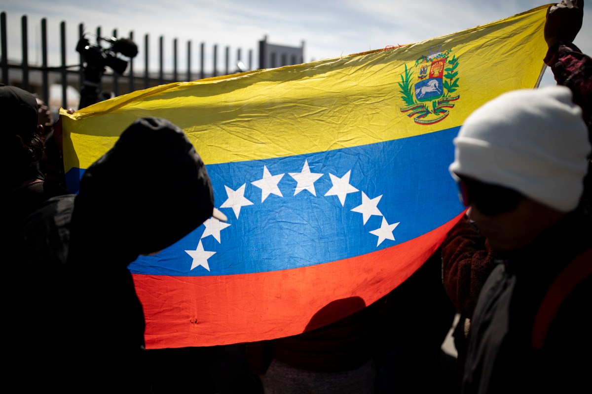Migrants hold up a Venezuelan flag near the migrant center in Juarez, Mexico on March 28, 2023. The Trump administration halted immigration applications for people from 19 countries, including Venezuela, in late November.